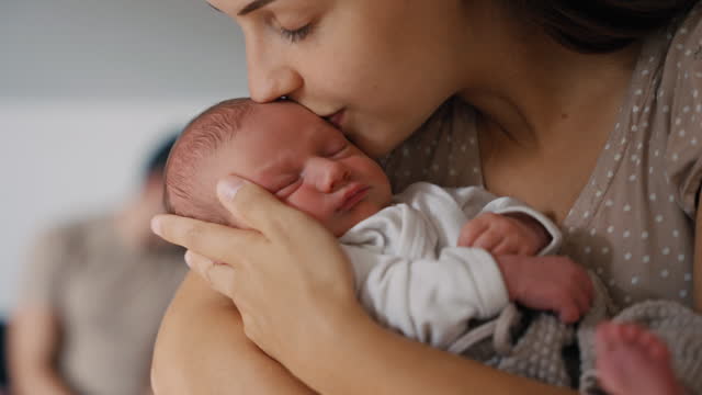 SLO MO Loving Young Woman Carrying Sleeping Newborn Daughter in her Arms and Kissing at Home