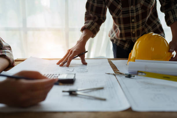 istock multi ethnic engineer brainstorming and measuring for cost estimating on blueprint and floor plan drawings about design architectural and engineering for houses and buildings 1729356047