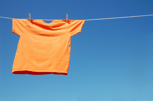 Picture of a orange t-shirt drying on the rope.See Also: