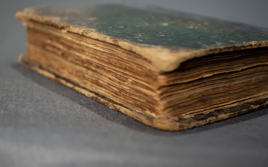 A battered book. An old book lies on a gray background. Very old close-up book.