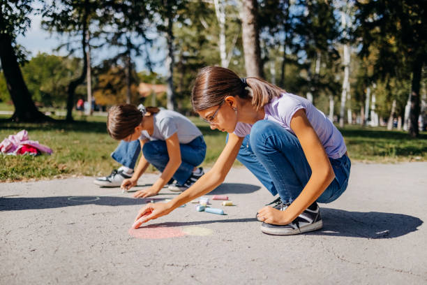 istock Girls having fun in public park drawing with chalk 1729364625