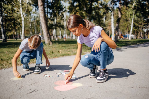 istock Girls having fun in public park drawing with chalk 1729365159