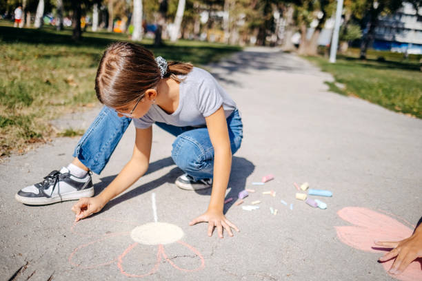 istock Girls having fun in public park drawing with chalk 1729365160