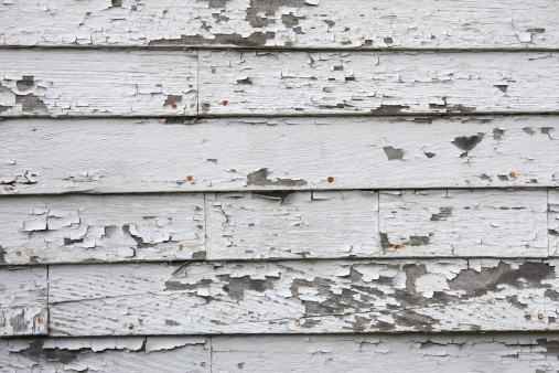 Peeling paint on the wall. Panorama of a concrete wall with old cracked flaking paint. Weathered rough painted surface with patterns of cracks and peeling. Grunge texture for wide panoramic background