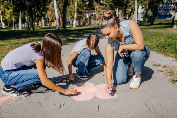 istock Girls having fun in public park drawing with chalk 1729367341