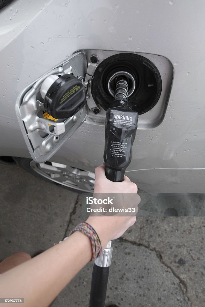 That'll be $4,975.99, please. Young woman fills the tank of a hybrid vehicle. Adult Stock Photo