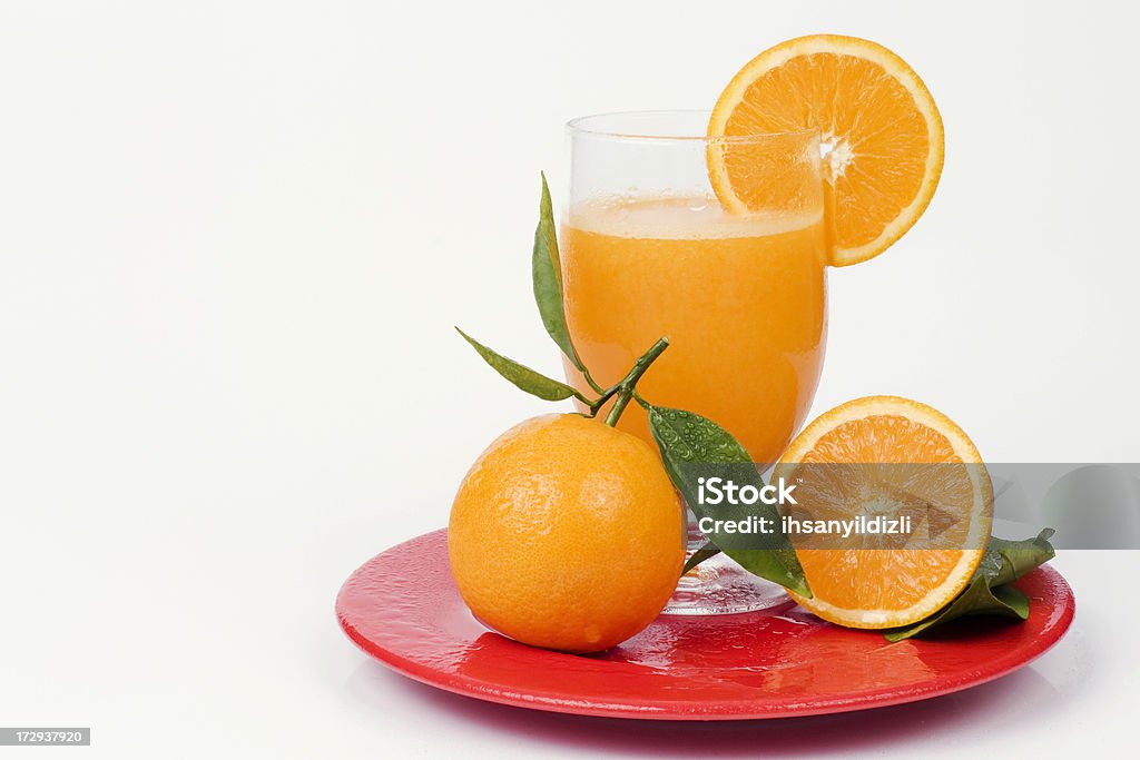 Orange A glass of fresh orange juice and oranges on a red plate,on isolated background. Citrus Fruit Stock Photo