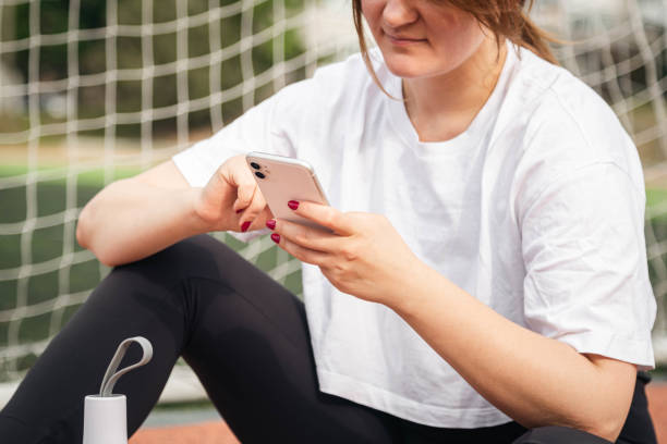 istock A woman uses a smartphone while sitting on a treadmill at the stadium. 1729379747