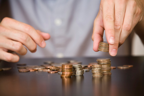 A stack of coins are being arranged by a person out of frame. 