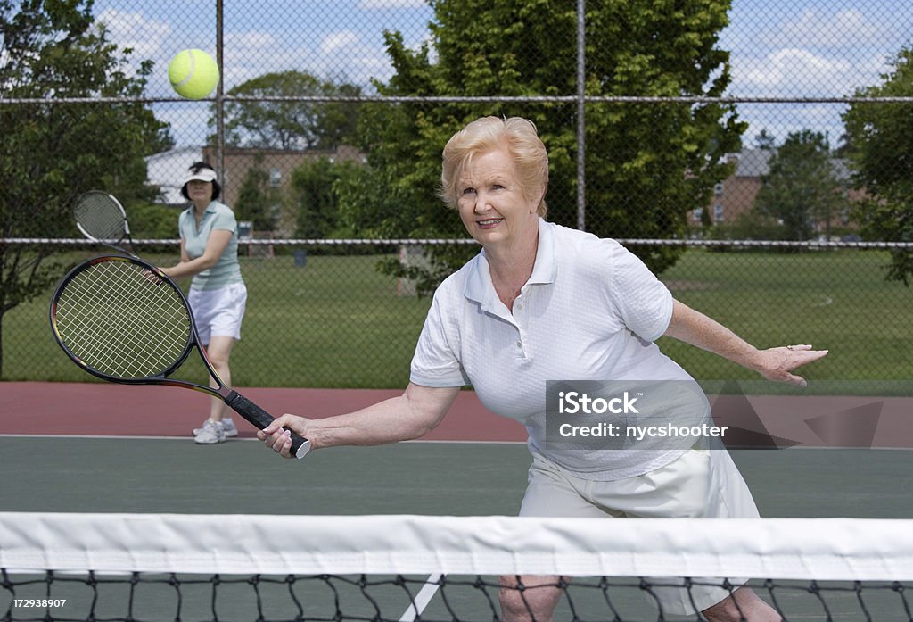 Старший женщина, играя в теннис с двуспальными кроватями - Стоковые фото Теннис роялти-фри