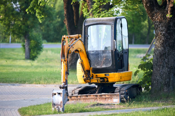 istock Tracked orange mini excavator digger near road green with trees on background with copyspace. 1729390440