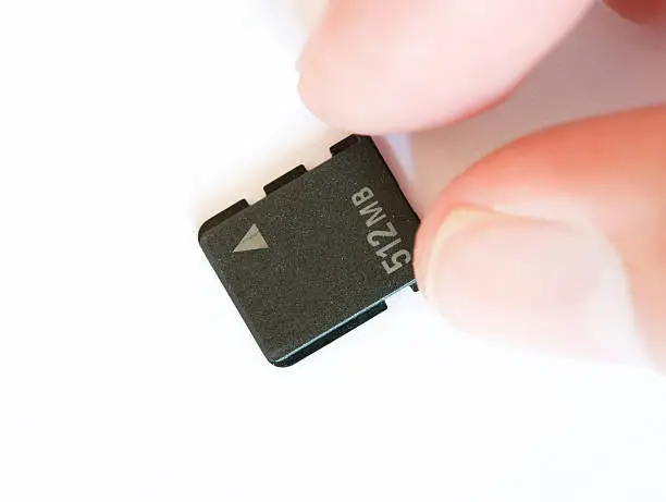 "Close-up of a very small memory card, Micro SD, held by fingers."