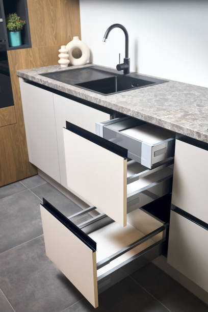istock Horizontal sliding pull out drawer cabinet shelves storage in kitchen cupboard with beige panels under stoneware countertop toptable black sink basin and facet. 1729399282