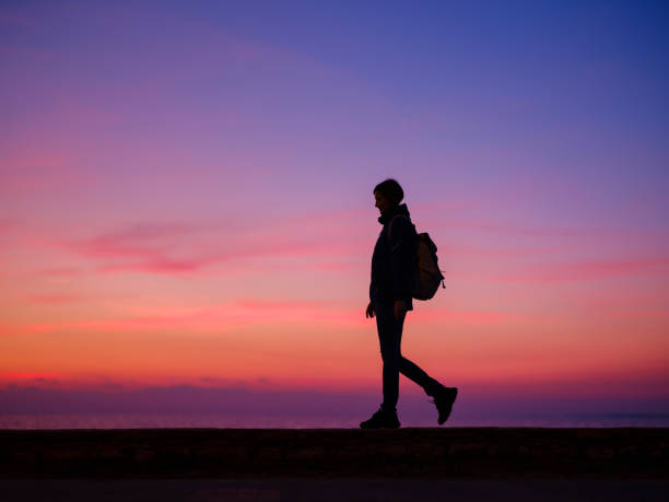 Woman tourist against colorful sunset sky. Travel, tourism concept. Active lifestyle and success idea gesture.