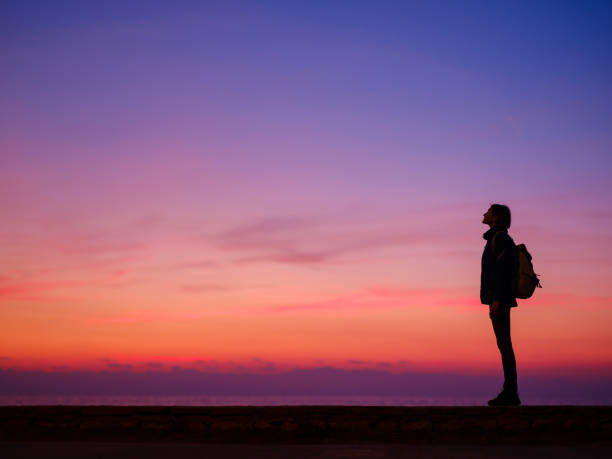 Woman tourist against colorful sunset sky. Travel, tourism concept. Active lifestyle and success idea gesture.