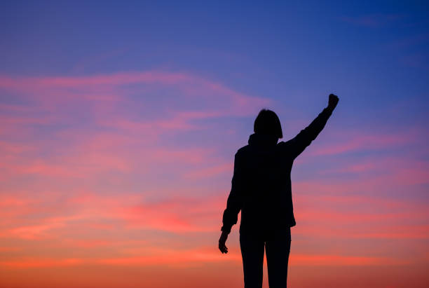 Woman tourist against colorful sunset sky. Travel, tourism concept. Active lifestyle and success idea gesture.