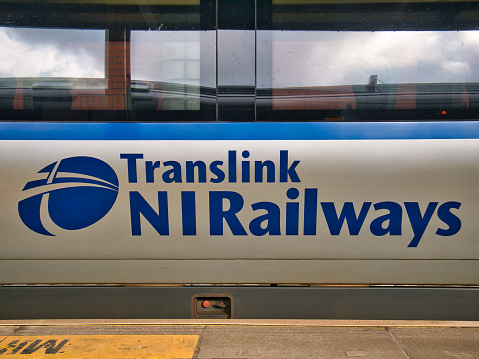 Blue corporate branding on the side of a grey - silver Translink railway carriage in Northern Ireland, UK.