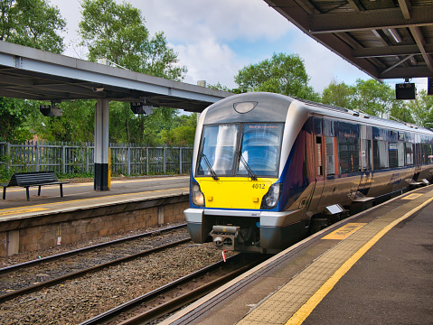A local commuter train arrives at a deserted platform at Lanyon Place Station in Belfast, Northern Ireland, UK. Taken on a sunny day in summer.