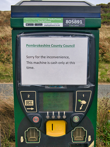 A temporary paper printed sign on a parking meter at Newgale Beach on the Pembrokeshire Coast in Wales, UK advises motorists that only cash payments can be made.