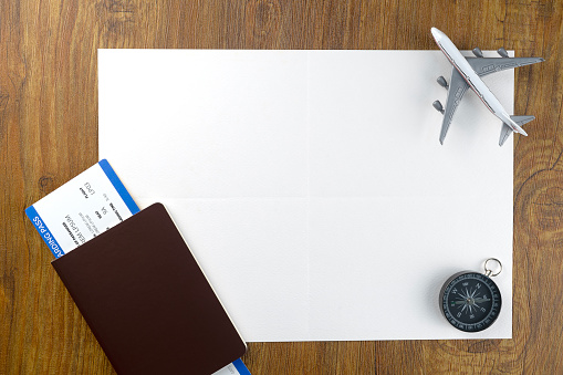 Passport with boarding pass and blank paper for mock up on wooden texture background. Tourism and travel concept. Top view. Flat lay.