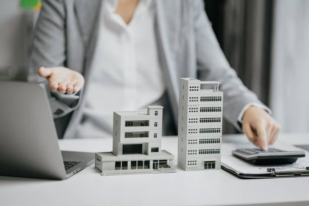 istock home loan officer uses a calculator with a house plan on a table. 1729424801