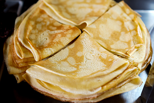 A close-up photo of cream-filled crepes piled up on a food tray.