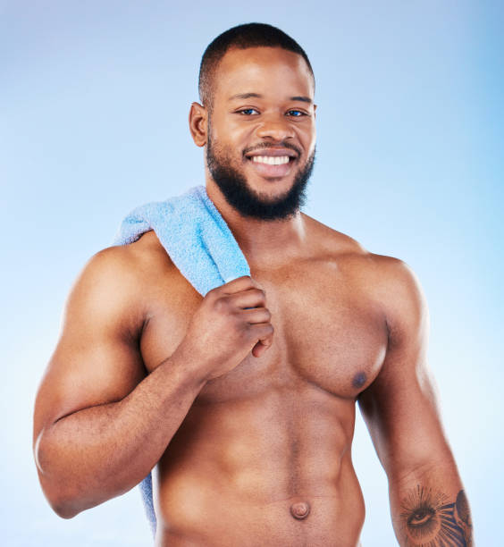 portrait serviette, douche et soin de la peau d’un homme noir avec le bonheur du muscle bodybuilder. nettoyage, soins personnels et bien-être de l’entraînement au gymnase et de l’exercice avec fond isolé, studio et bleu - shower portrait male beauty chest photos et images de collection