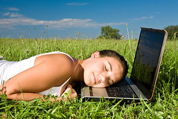 молодые красивые девушки, спать на ноутбуке на открытом воздухе - lying down women laptop freedom стоковые фото и изображения