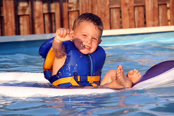 criança usando um colete salva-vidas na azul piscina - life jacket equipment safety jacket - fotografias e filmes do acervo