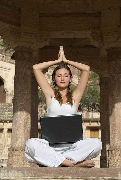 Woman meditating with Laptop stock photo