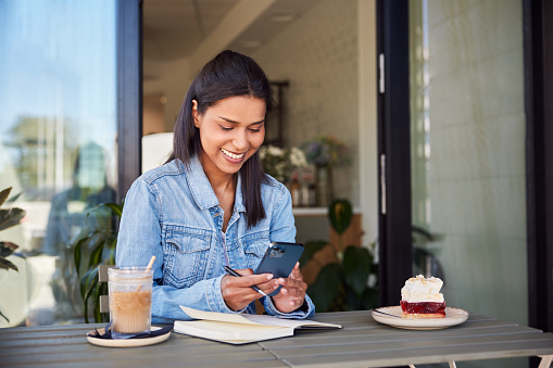 Young woman with mobile phone and notebook at a cafe