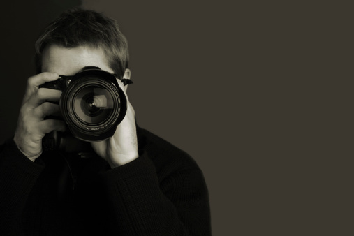 A photographer with a nice camera.  Focus is on the lens.