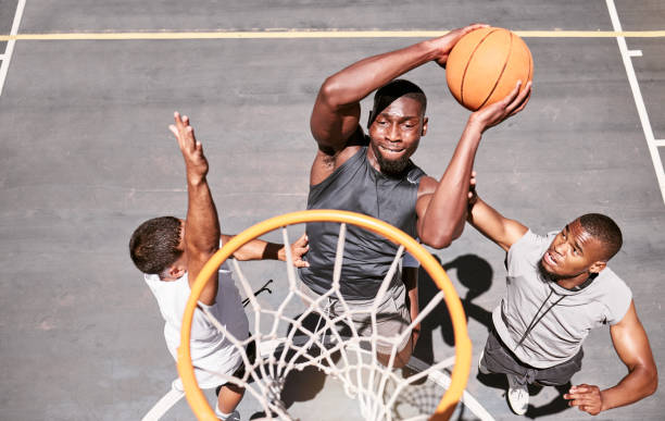istock Basketball players blocking a player from dunking a ball into net to score points during a match on sports court from above . Fit athletes jumping to defend in competitive game for recreational fun 1729458159
