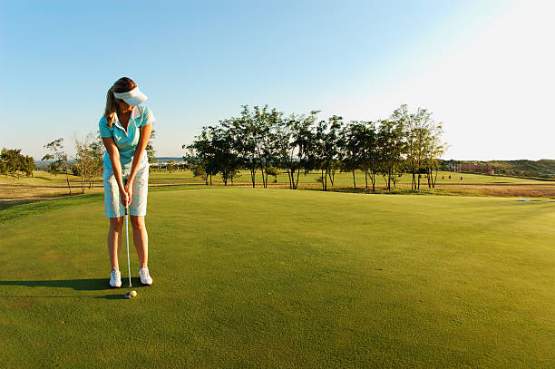 Woman on golf field ready to put ball Young woman playing golf. putting stock pictures, royalty-free photos & images