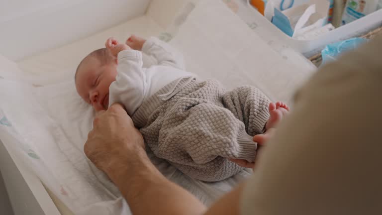 SLO MO High Angle of Father Dressing Newborn Baby Girl on Mat at Home