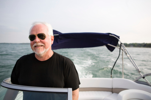 mature man steering a boat with a smile on his face.