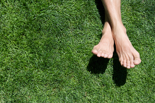 Man's bare feet cross on a patch of bright green grass