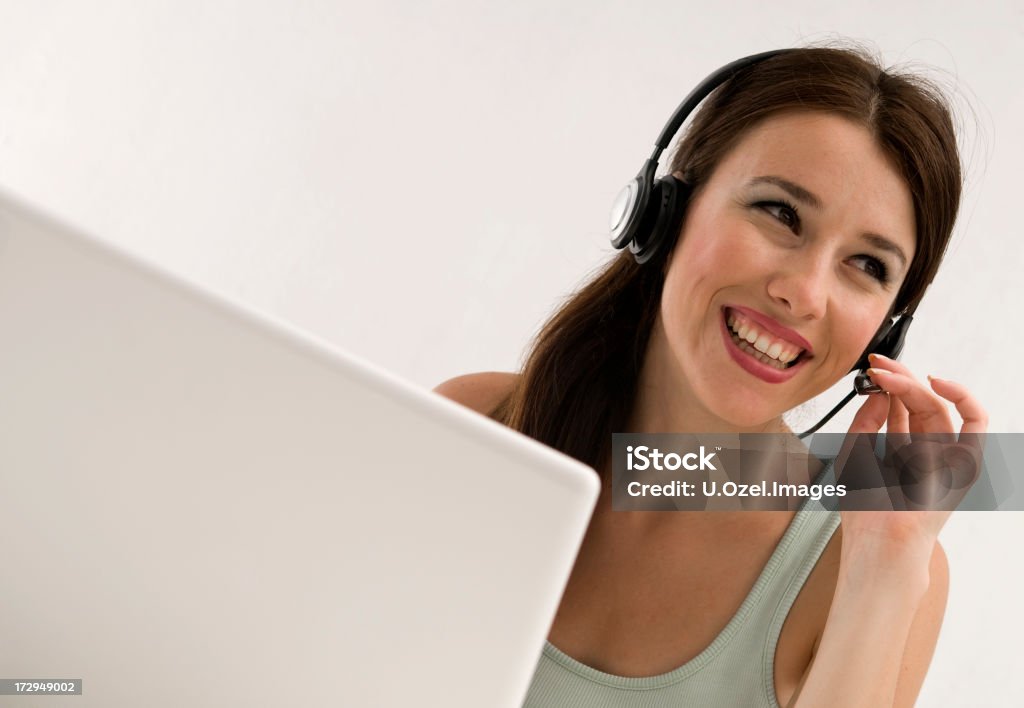 Most beautiful customer representative... Positive smiling young woman speaking with the customers on earphone... Working At Home Stock Photo