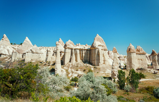 Unique geological formations in Love Valley in Cappadocia against blue sky in summer. Popular touristic area in Goreme, Nevsehir, Turkey