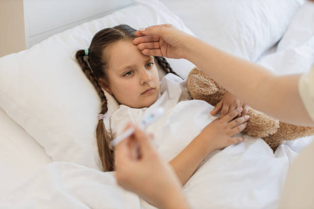 istock Upset sick girl lying in bed while mother using thermometer 1729497661