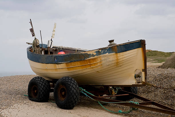Photo showing a traditional fishing boat in Kovalam Beach, Kerala, India, used by a group of Indian fisherman. Each morning at sunrise, the fishermen sail out with their boat (painted blue) and carefully set the large net, trawling the water and pulling it to the shore, catching small baby fish, as well as tuna, mackerel and Indian kingfish.