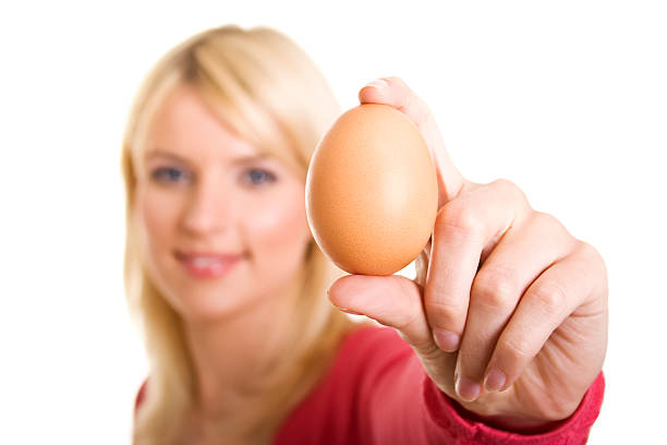 Jeune femme blonde tenant un œuf - Photo