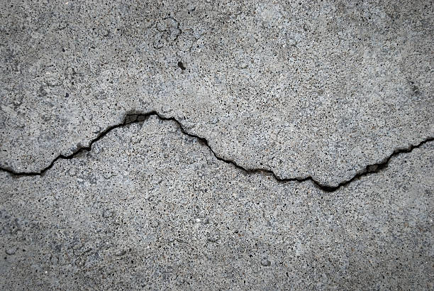Crack in grey concrete surface A crack runs across a cement floor cracked texture stock pictures, royalty-free photos & images