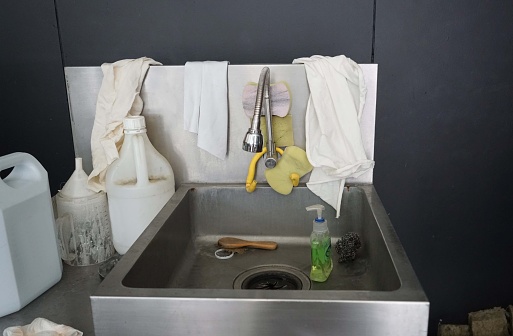 Dirty kitchen sink with cleaning supplies, cleaning service concept.