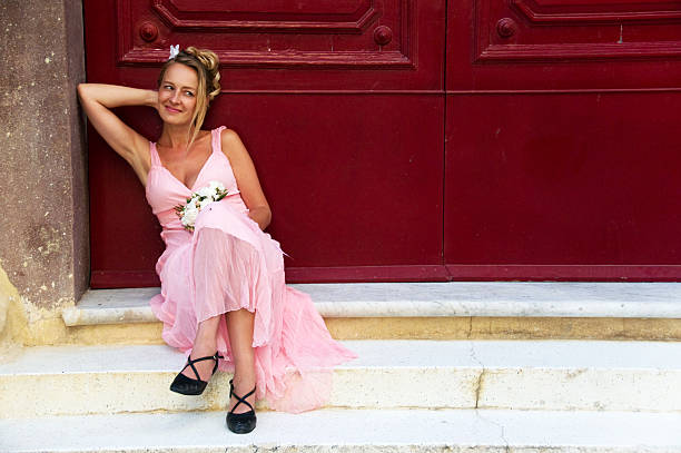a cute pink bridesmaid waiting at a red door.
