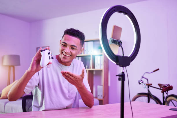 Streamer, live streaming and man gamer with review of console controller on social media for connection on vlog. Ring light, influencer and content creator or person speaking on internet show as host streamer, transmisión en vivo y hombre gamer con revisión del controlador de la consola en las redes sociales para la conexión en vlog. luz de anillo, influencer y creador de contenido o persona que habla en un programa de internet como anfitrión