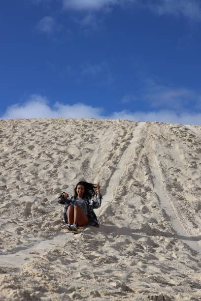 istock Woman sitting on the sand, joyfully sliding down a small hillside in Lancelin Sand Dunes, Australia 1729515930