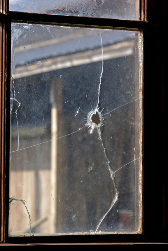 A bullet hole in an old window, used on a western movie set.
