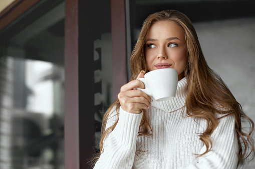 Portrait of young woman drinking coffee in cafe.