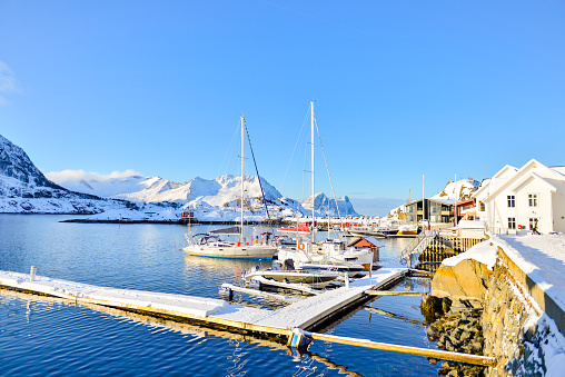 Marina in a bay at Hamn on the island Senja in Northern Norway on a winter day with fishing boats and sailing boats moored at the dock.